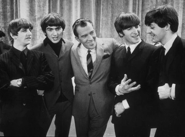 Ed Sullivan smiles while standing with the Beatles on the set of his CBS variety show Ed Sullivan smiles while standing with the Beatles on the set of his CBS variety show