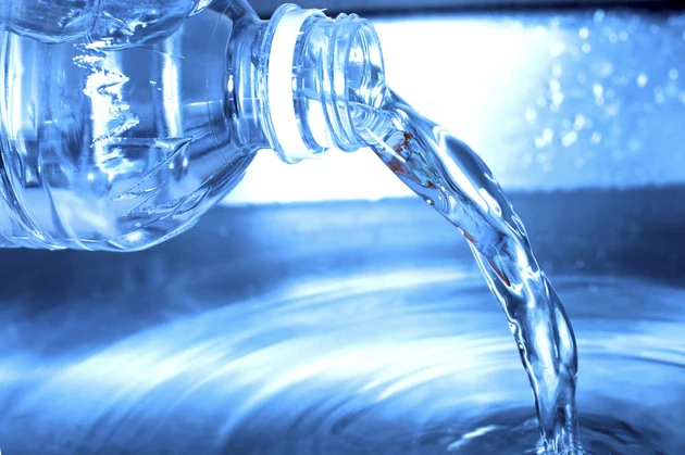 Water from a water bottle is being poured out into a pool of water