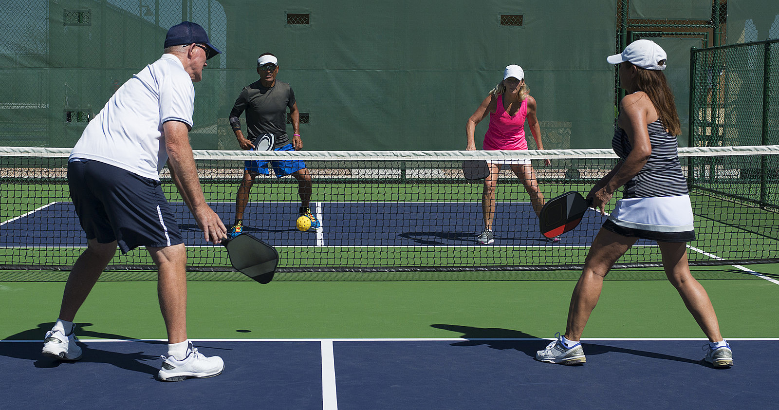 colorful action image of mixed doubled Pickleball match play